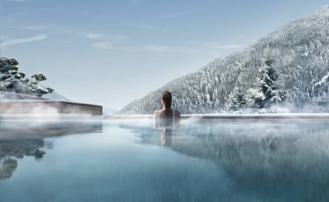 Heated infinity pool with views of snow-covered mountains