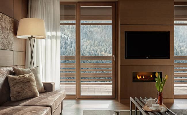 Living area with built-in gas fireplace and balcony access; forest views