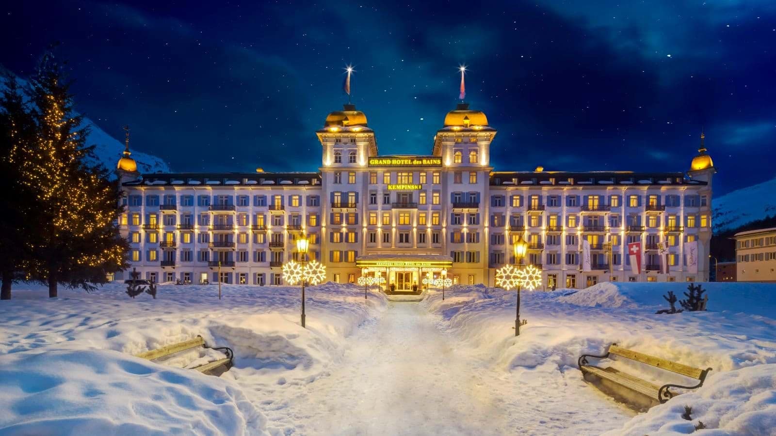 Hotel exterior at night with snow-covered grounds and holiday lighting