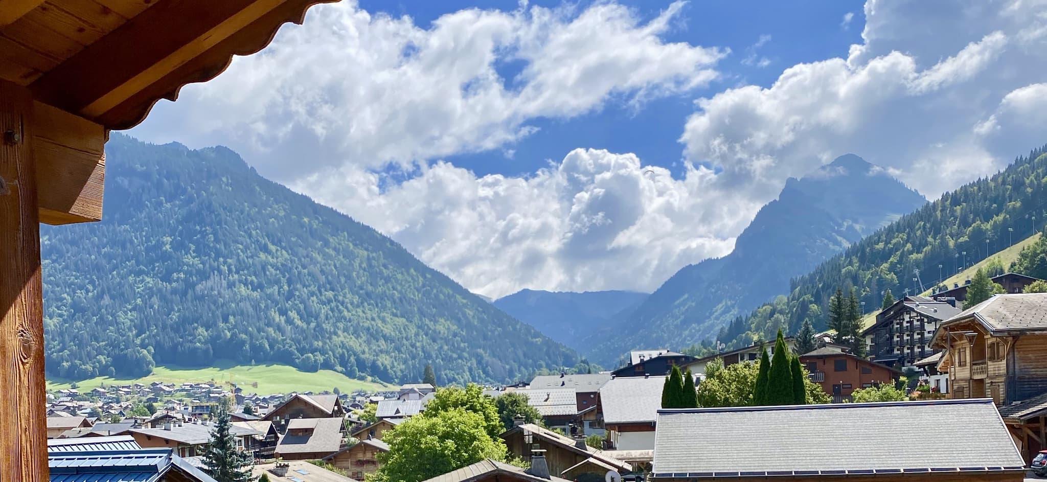 Balcony view overlooking alpine village, forested mountains, and verdant valley