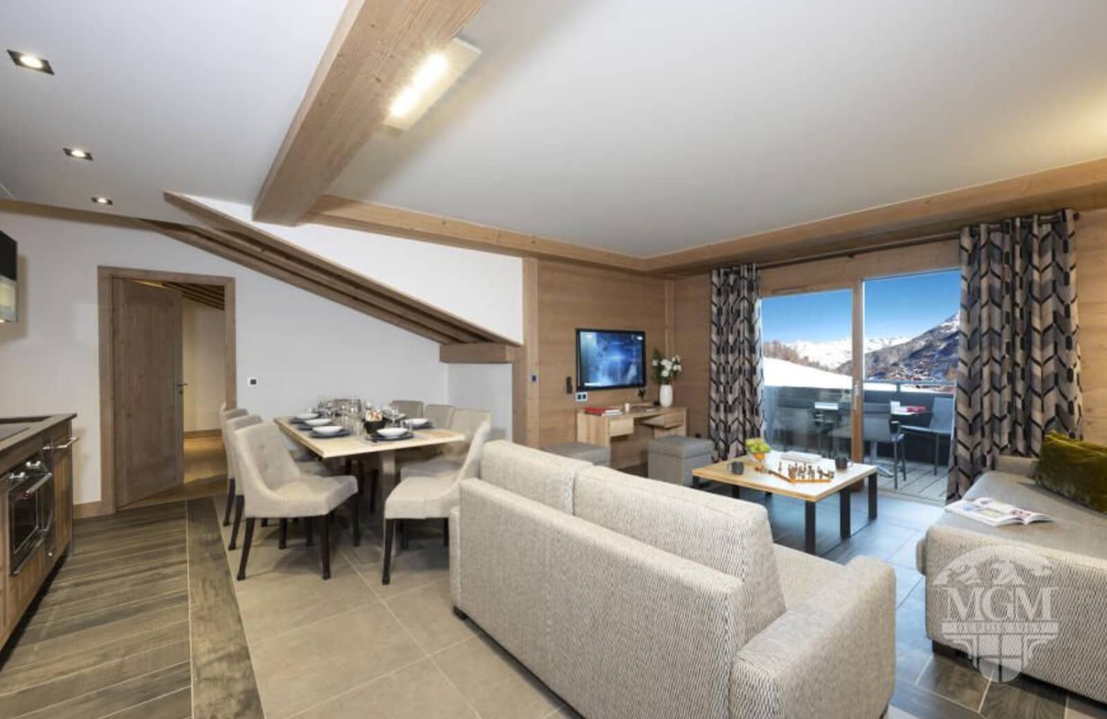 Open-plan living area with 6-person dining table and mountain-view balcony
