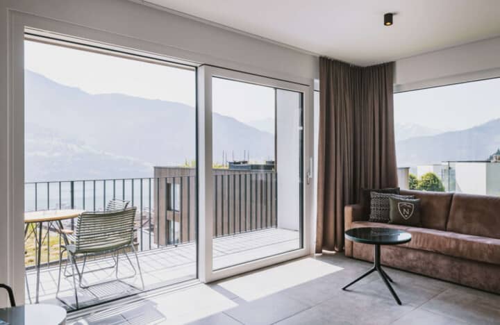 Living area with floor-to-ceiling glass doors and balcony with mountain views