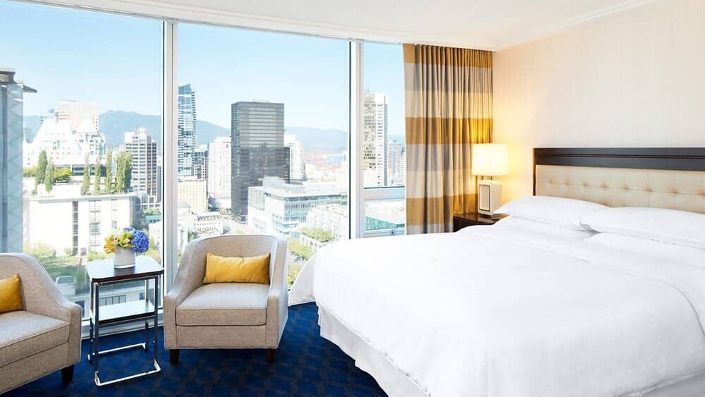 Primary bedroom with king bed and floor-to-ceiling city skyline views