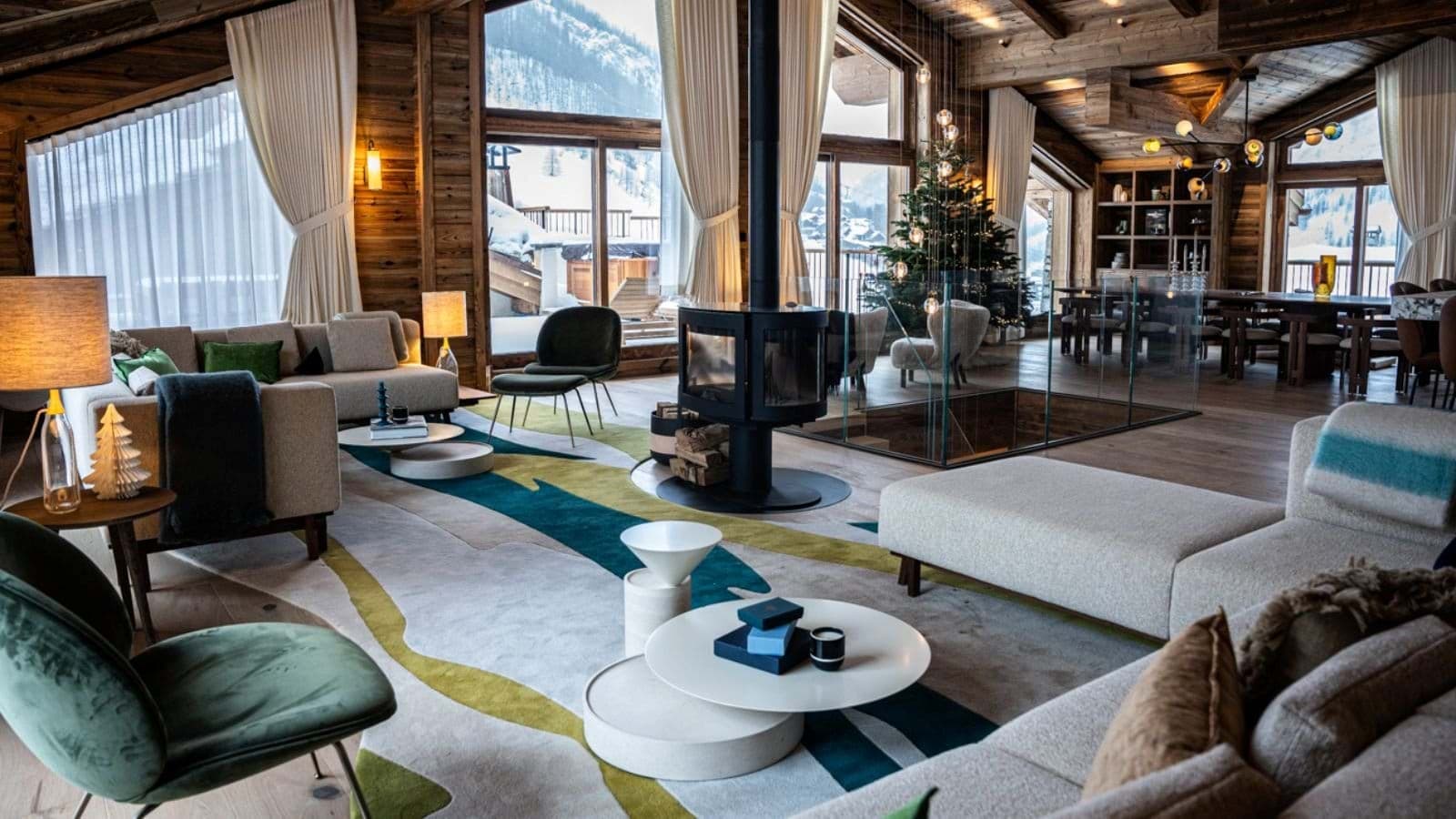 Open-plan living area with 360-degree wood stove and floor-to-ceiling mountain views