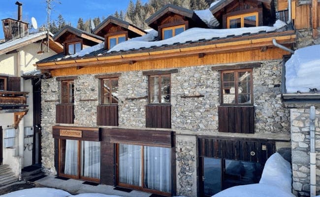 Stone and timber chalet facade with snow-capped dormer windows