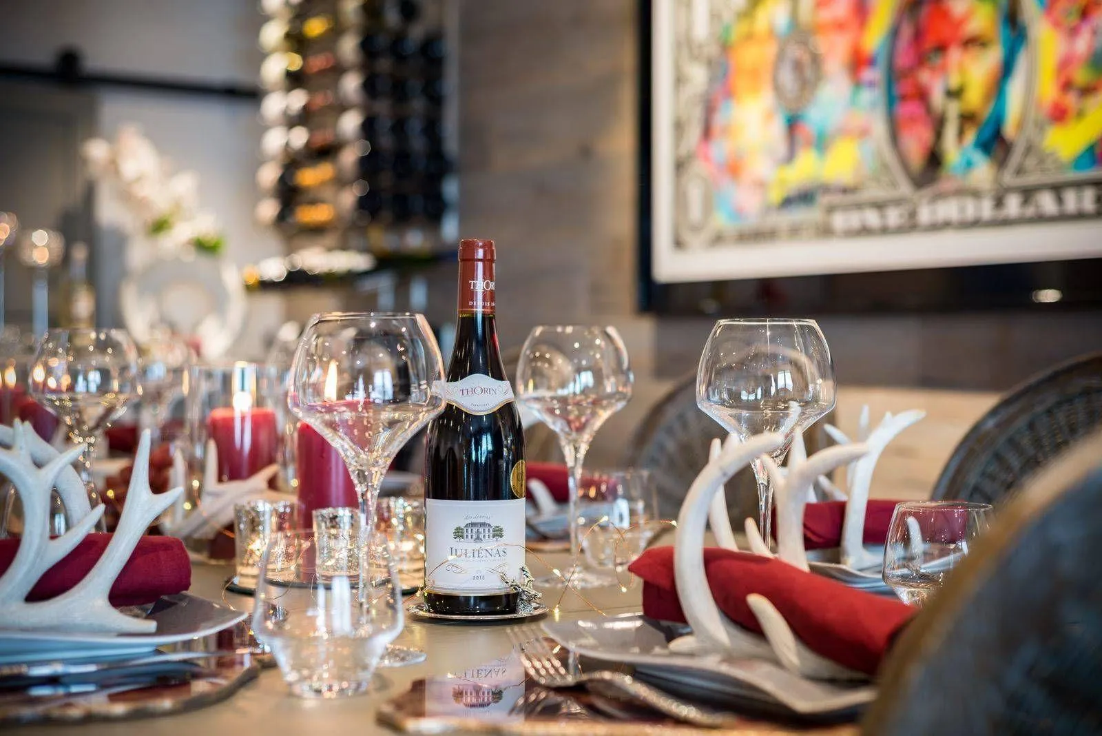 Dining table with place settings beside floor-to-ceiling wine storage