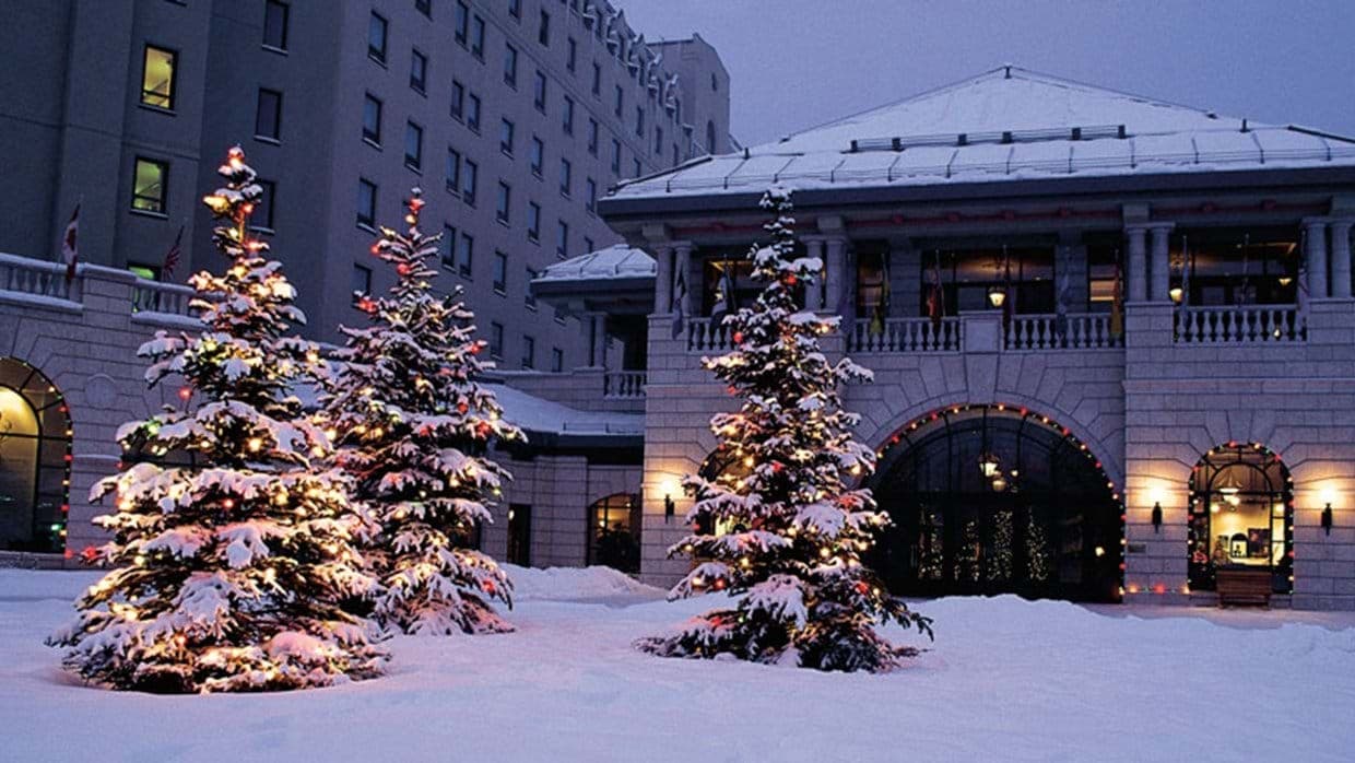 Hotel entrance at dusk with holiday lighting and snow-covered courtyard