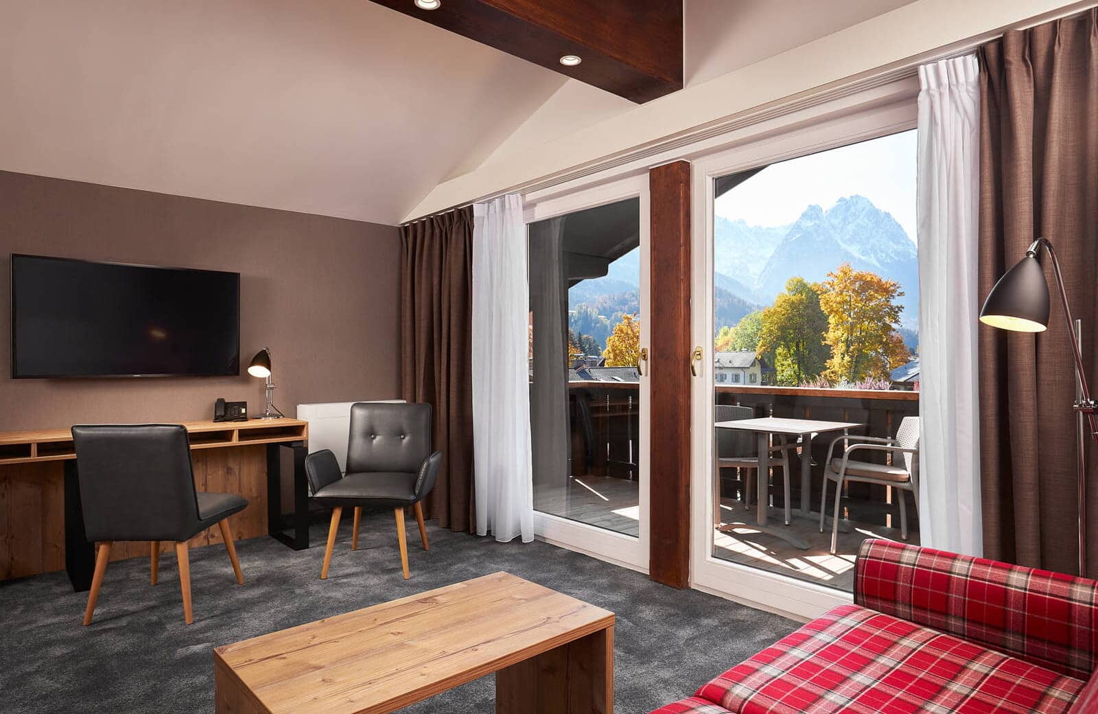 Living area with desk and balcony access; mountain views