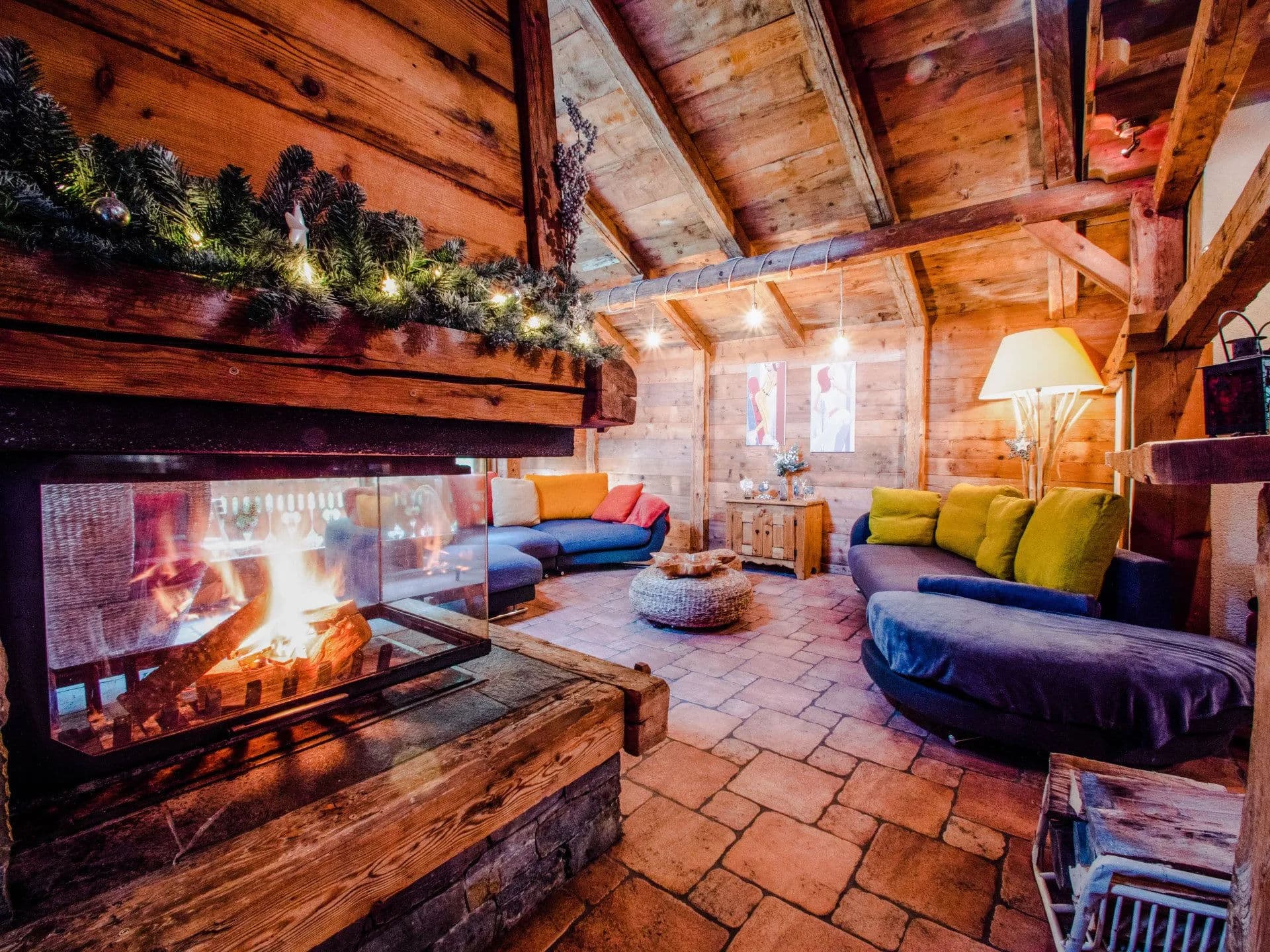 Vaulted timber lounge with gas fireplace, dual curved seating, and garland-draped beams