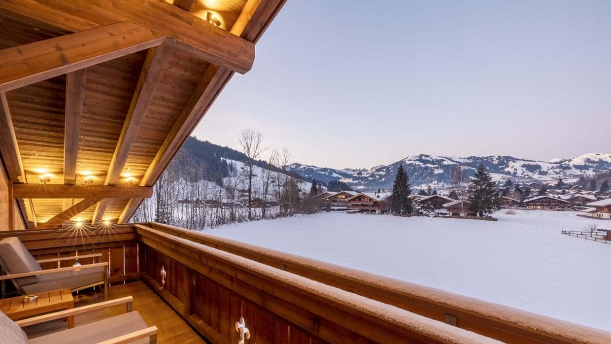Covered balcony with seating for two and snow-covered valley views