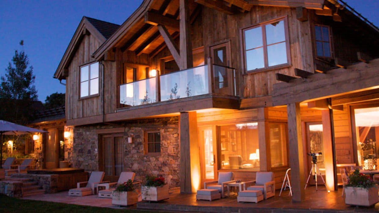 Stone patio with hot tub and upper-level glass balcony