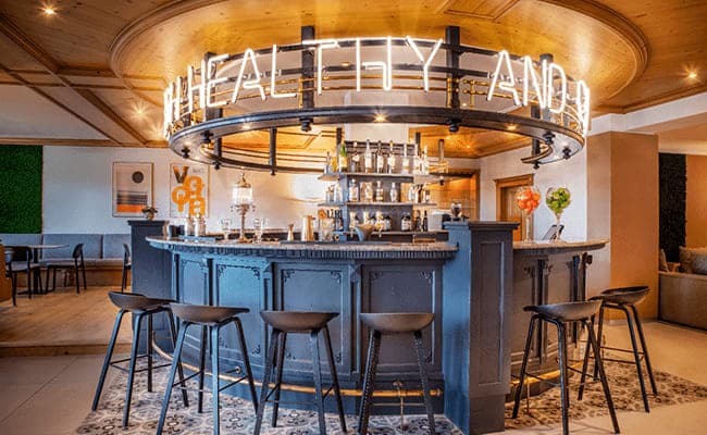 Circular cocktail bar with neon signage and seating for six