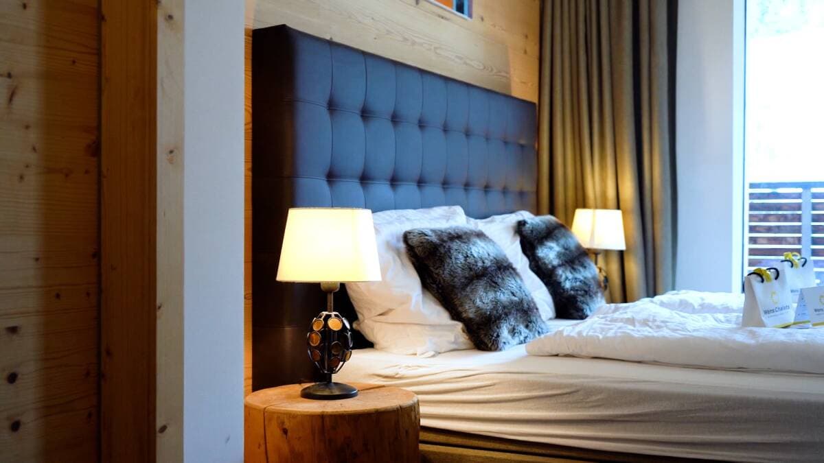 Primary bedroom with navy tufted headboard and heated bedside lamps