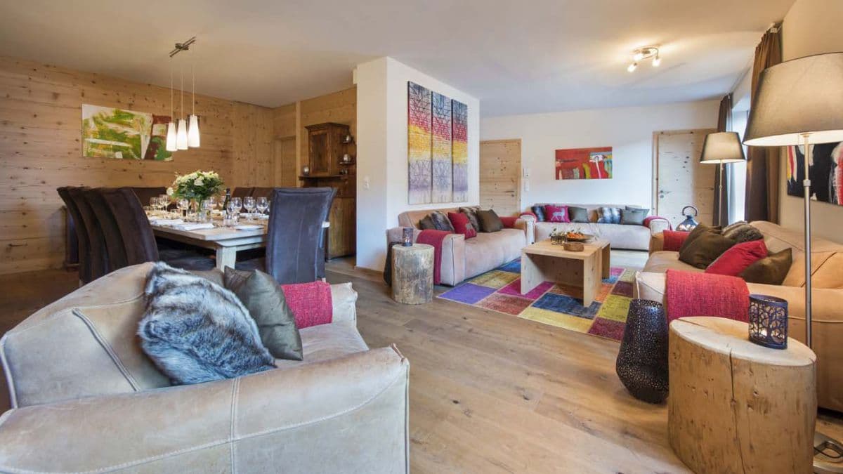 Open-plan living area with dual seating zones; colorful accent pillows and patterned rug define spaces