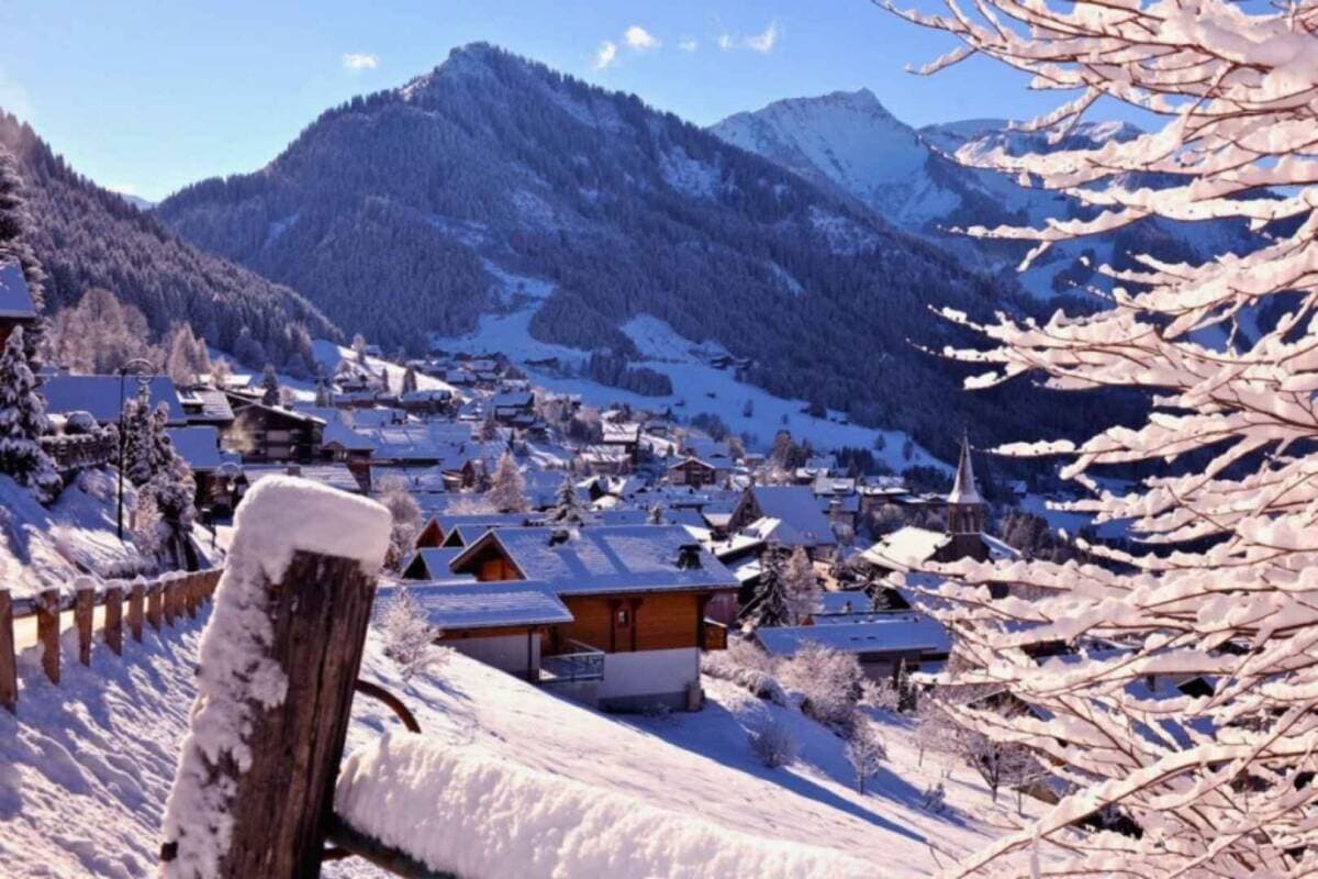 Alpine village nestled in valley; mountain views frame snowy landscape