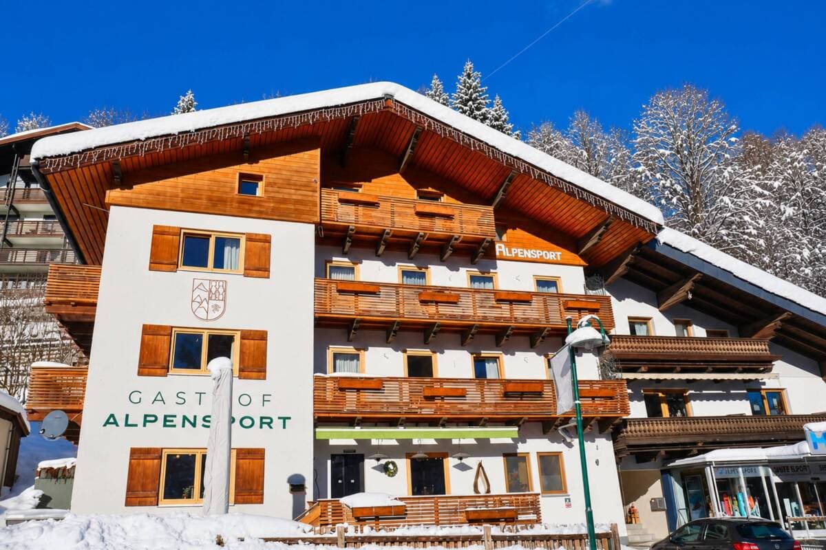 Alpine hotel exterior with wood and white facade; ski-in/ski-out location in snow-covered resort