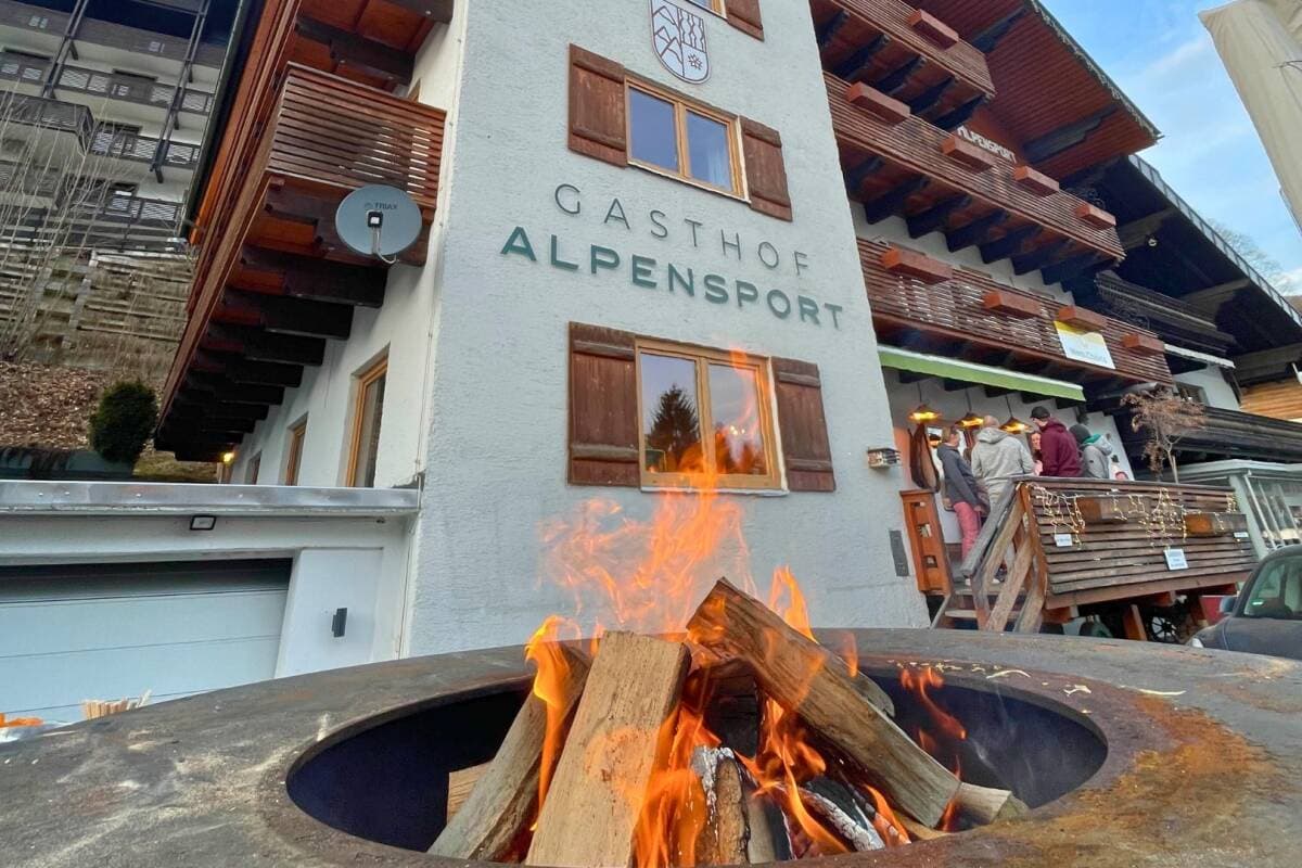 Outdoor fire pit at Gasthof Alpensport; guests gathering on adjacent deck