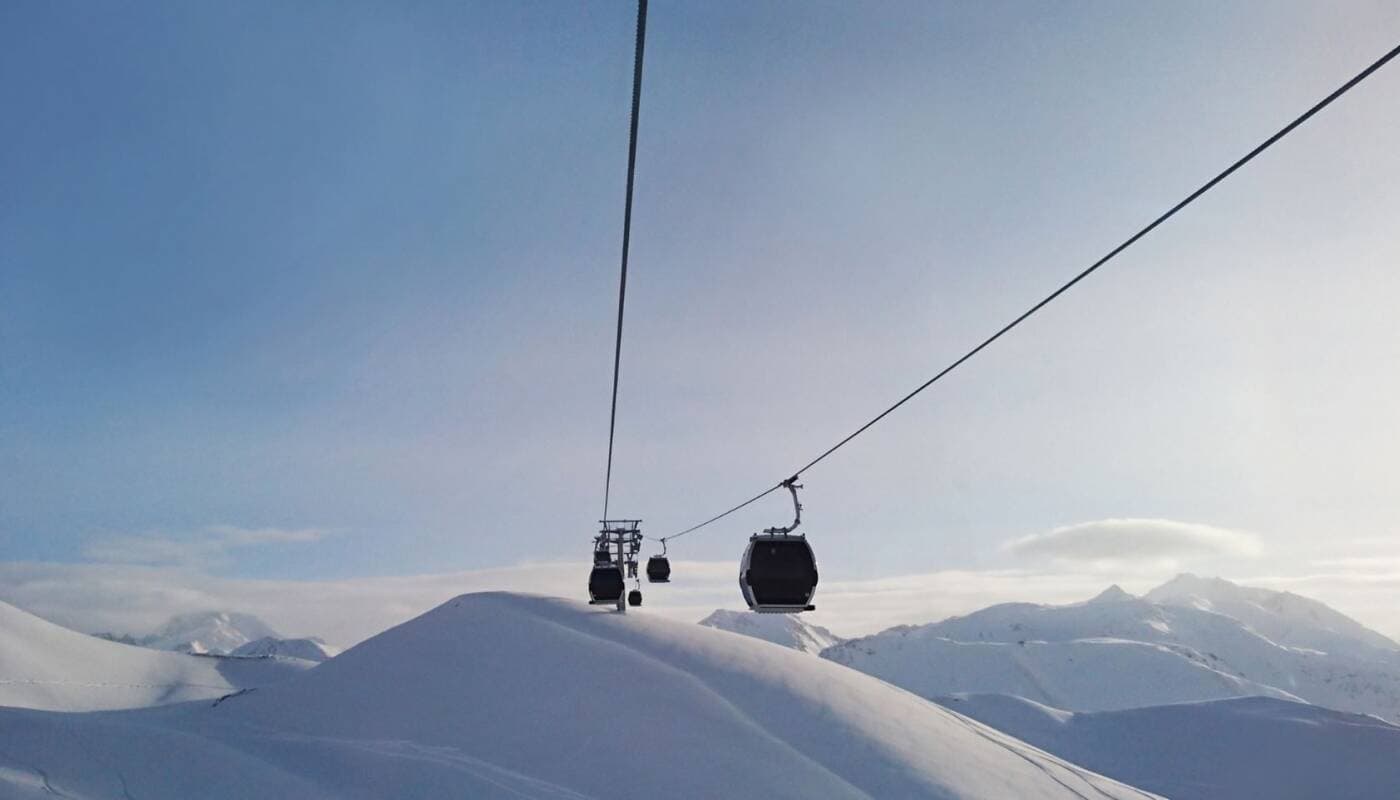 Ski lift ascending snowy mountain slope with valley views beyond
