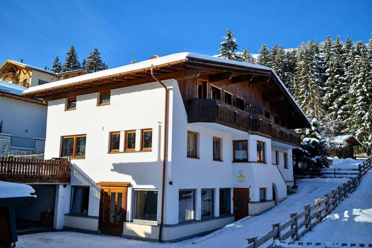 Alpine chalet exterior with heated wooden balcony and snow-covered grounds