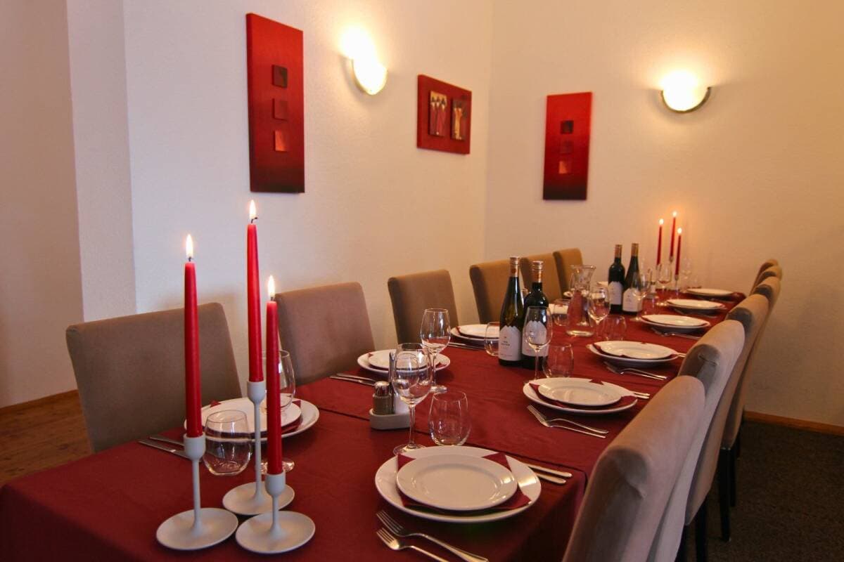 Private dining room seats 8; red table with place settings and wine service