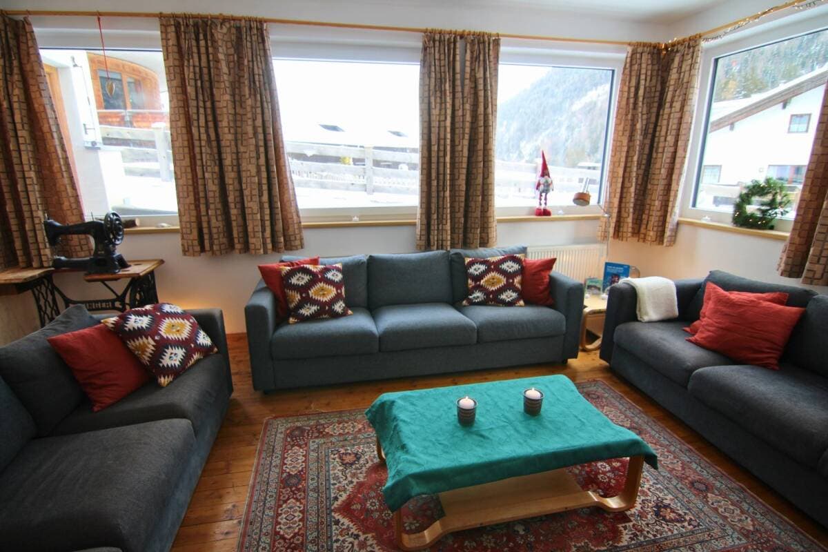 Living room with three seating areas; mountain valley views from wraparound windows